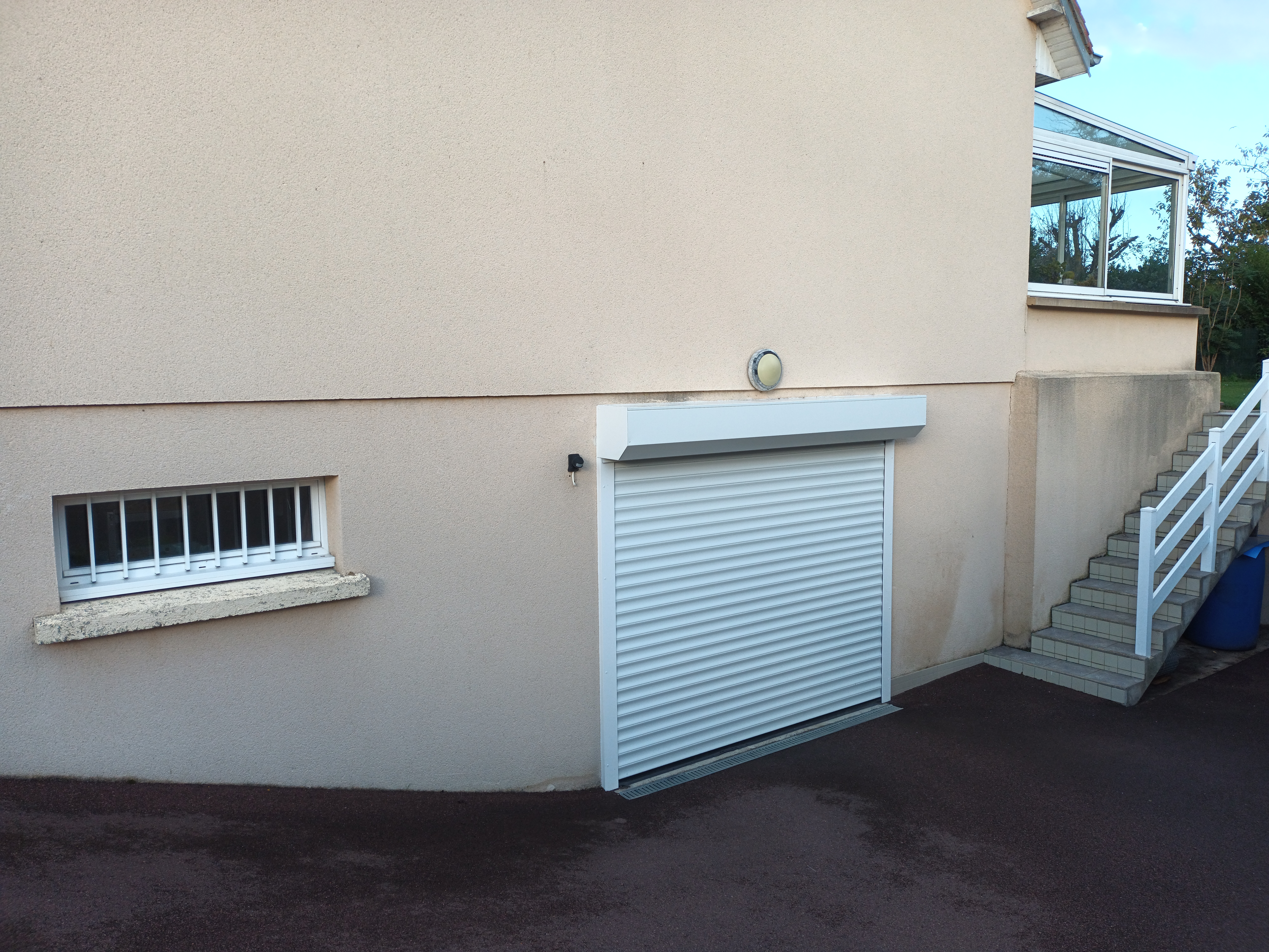 Entrée de garage avec porte et escaliers adjacents.