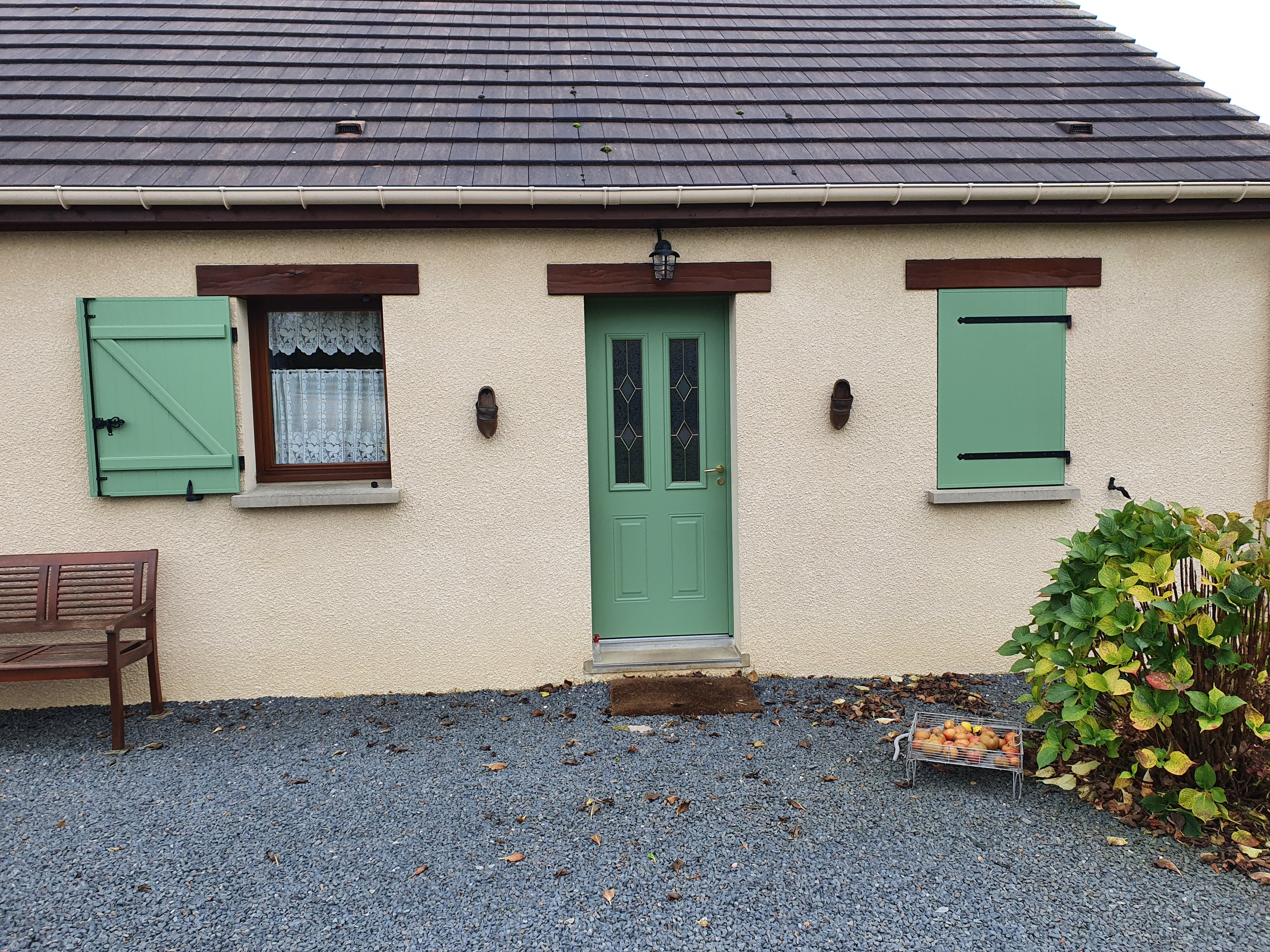 Maison avec volets verts et banc en bois.