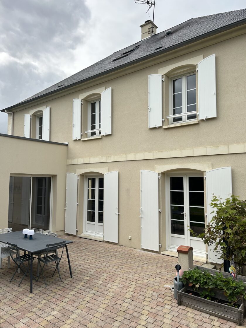 Façade de maison avec terrasse en pavés.