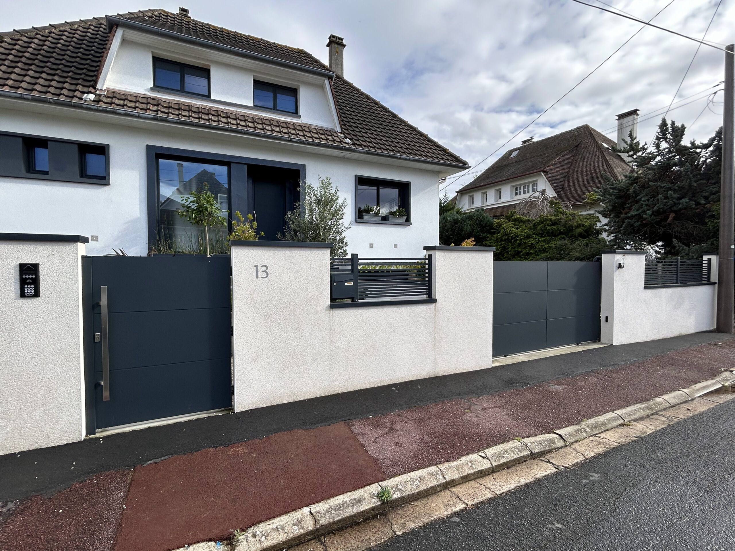 Maison moderne avec portail gris et jardin.