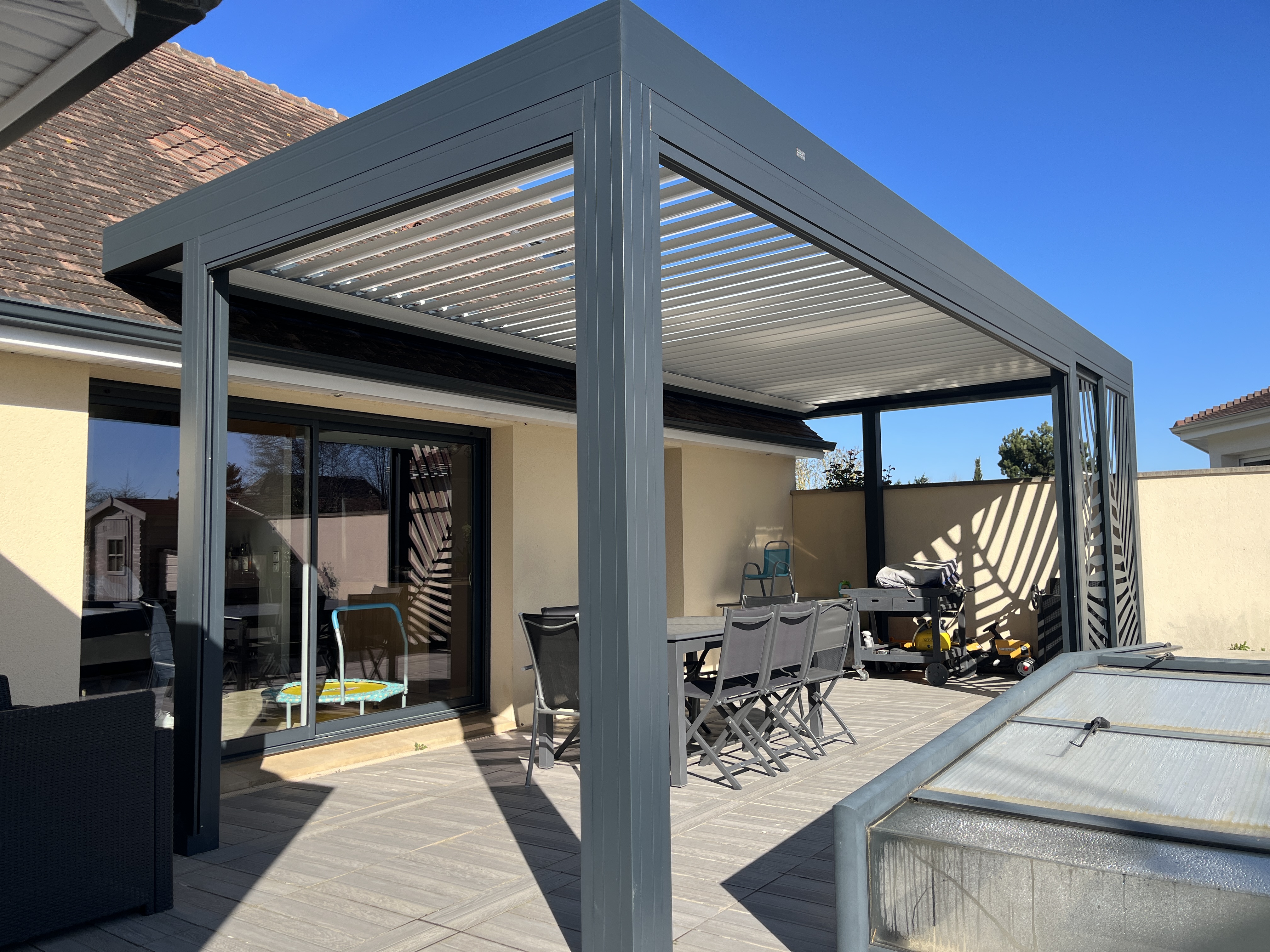 Pergola moderne sur terrasse ensoleillée.