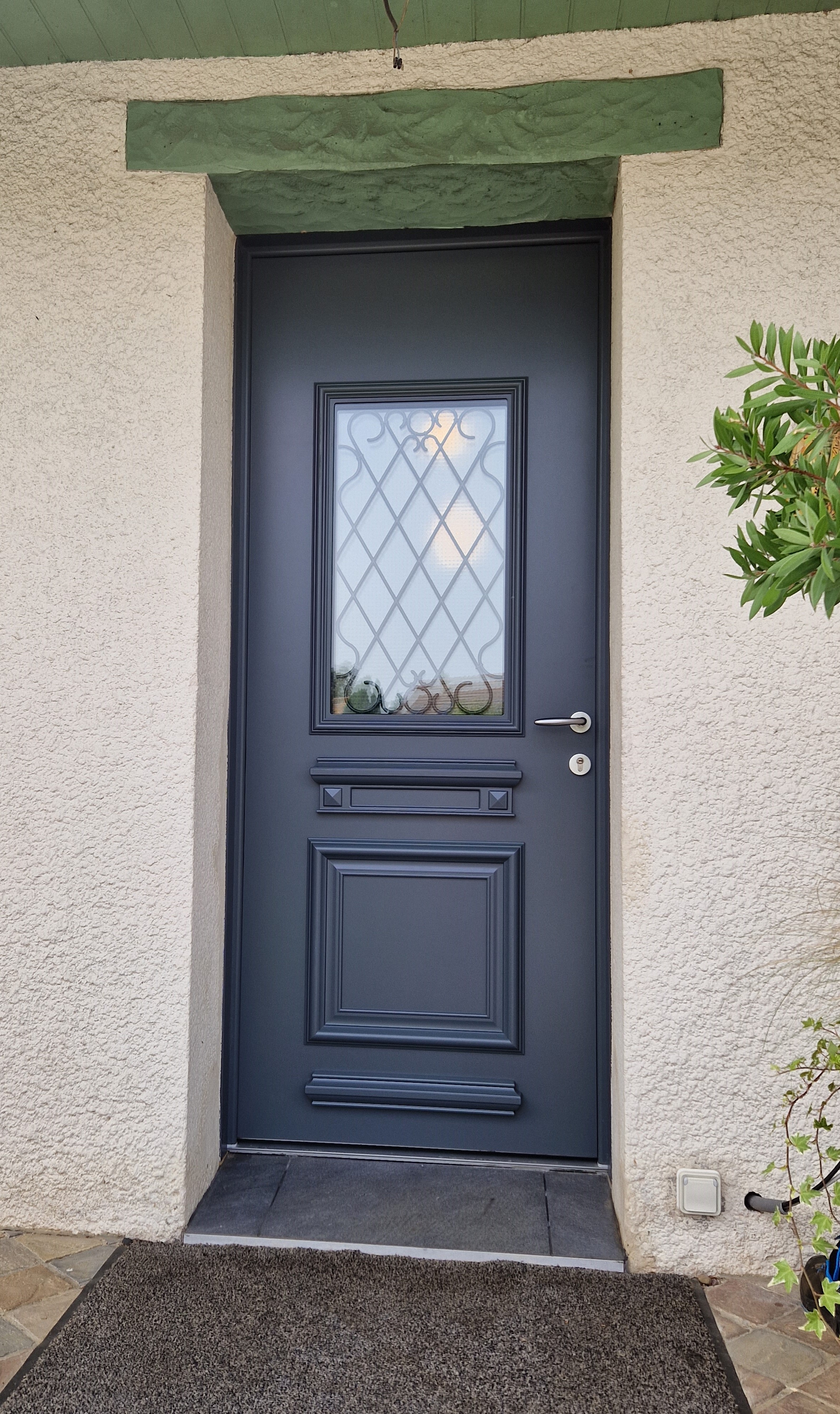 Porte bleue avec vitrail géométrique.