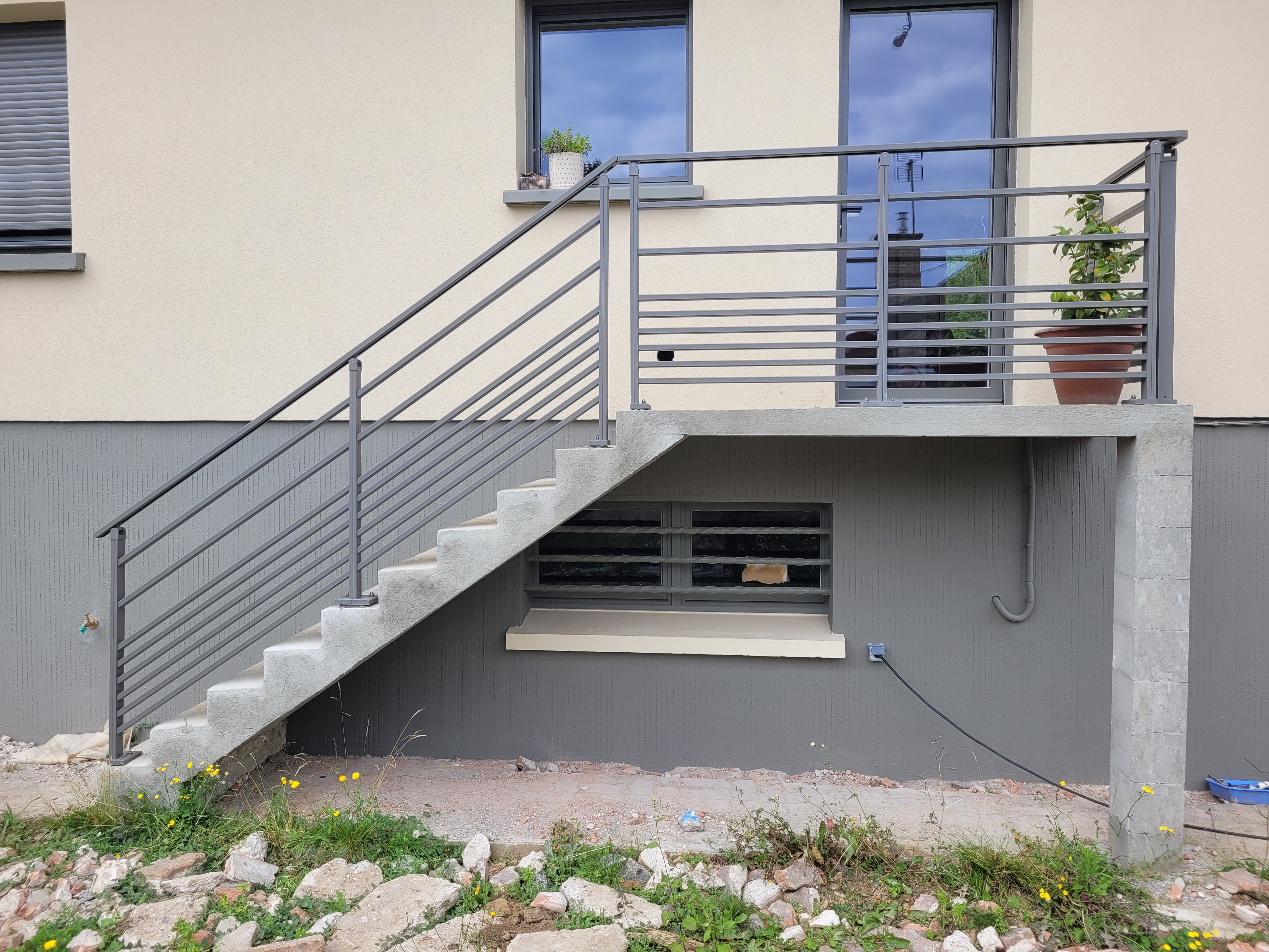 Escalier extérieur en béton avec balustrade métallique.
