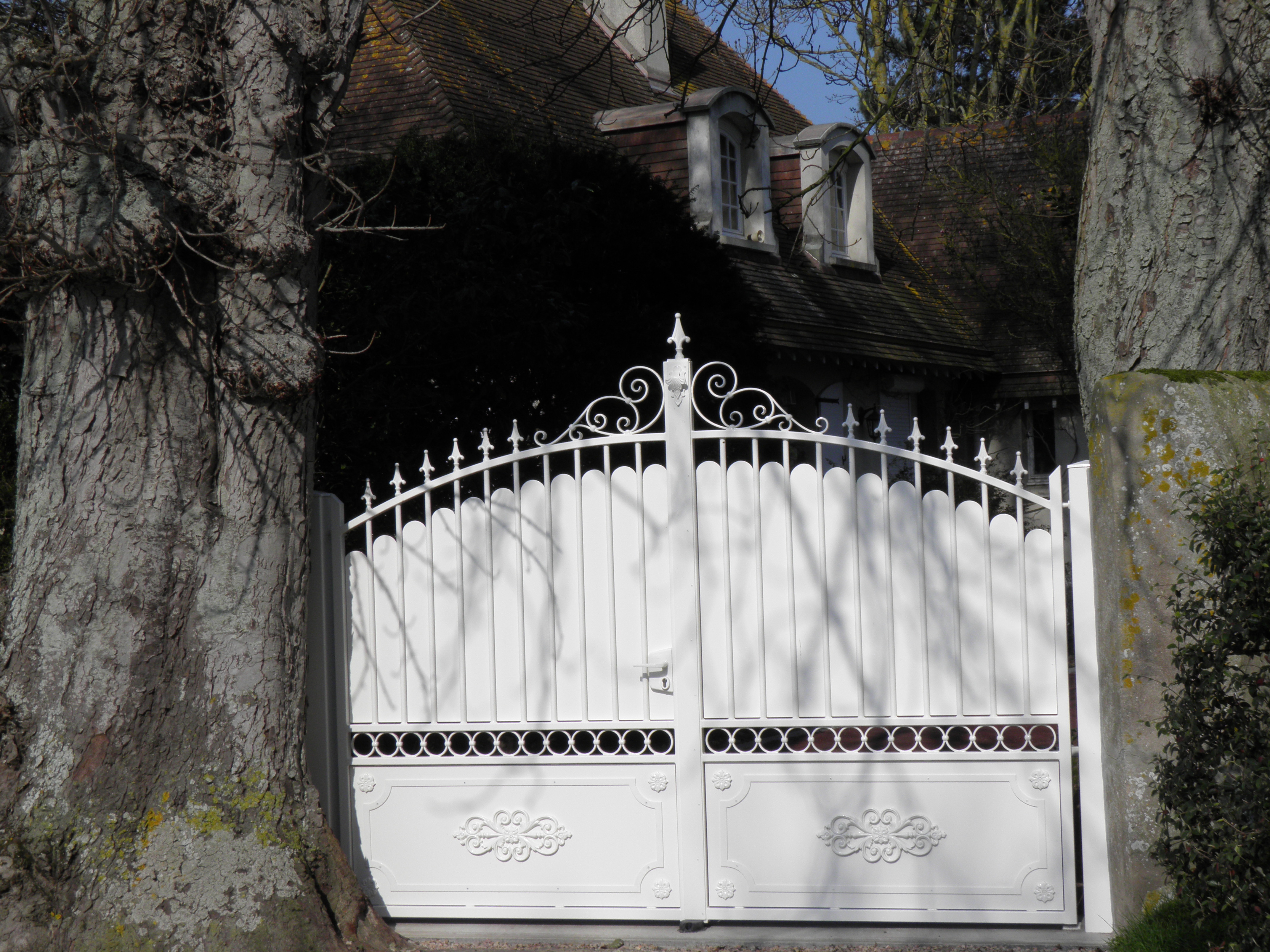 Portail blanc décoratif devant une maison.