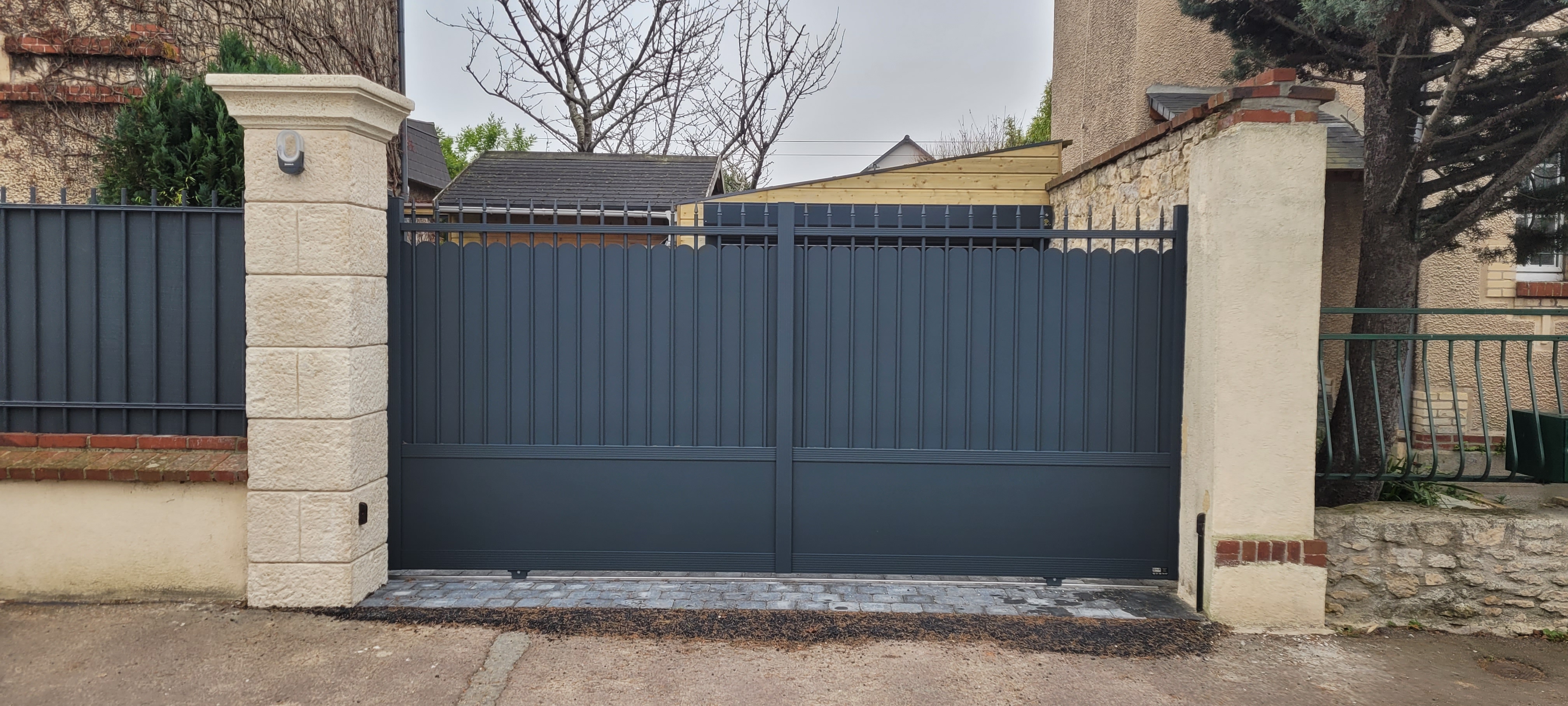 Portail métallique gris devant une maison.