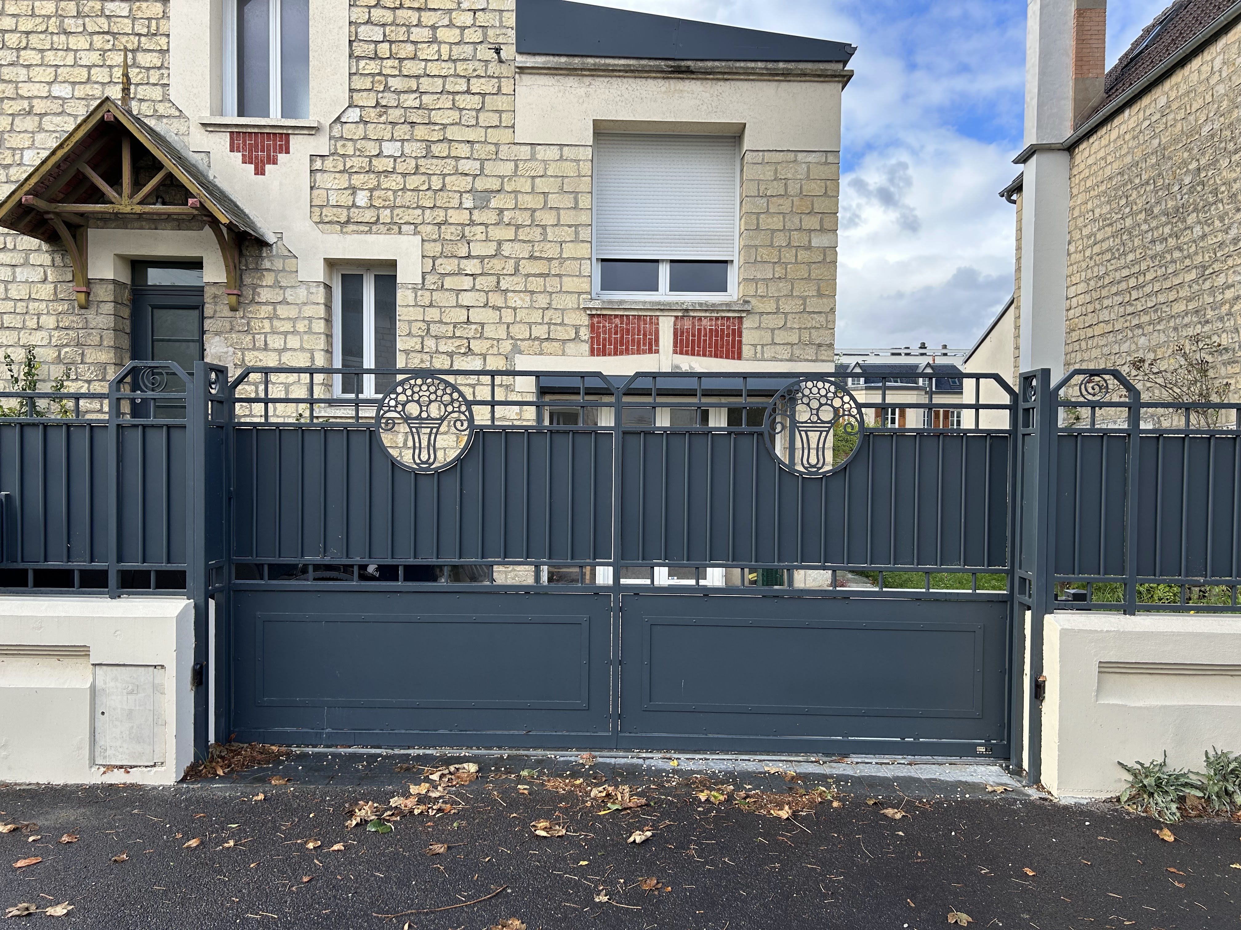 Portail gris devant une maison en pierre.