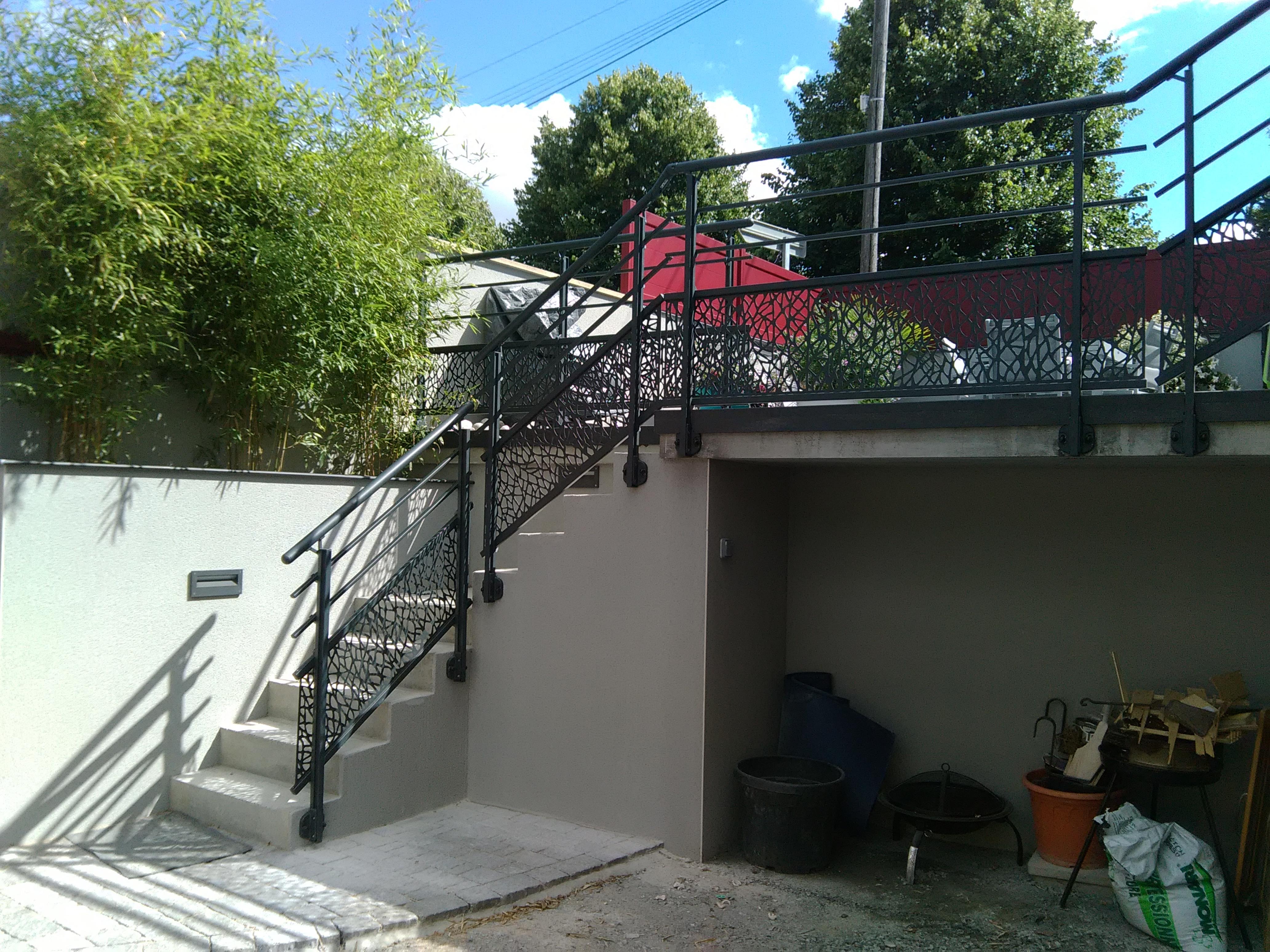 Escalier extérieur en métal avec végétation.