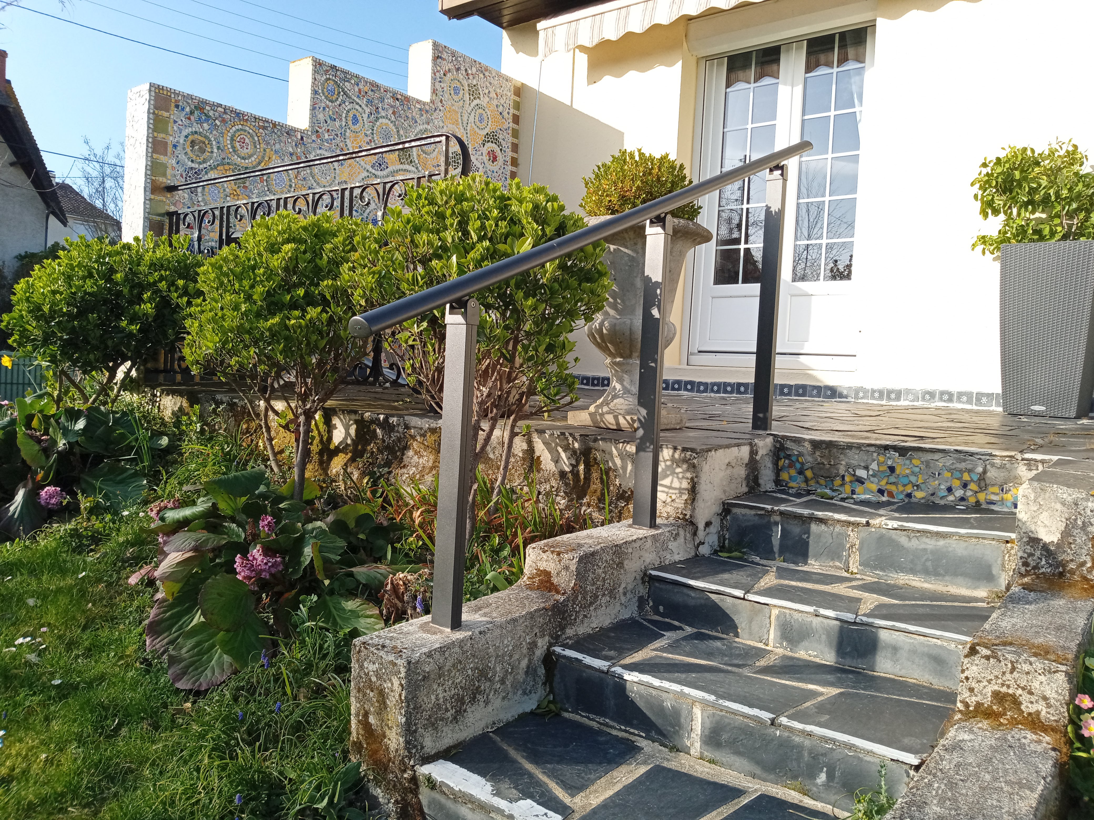 Escalier en pierre menant à une terrasse fleurie.