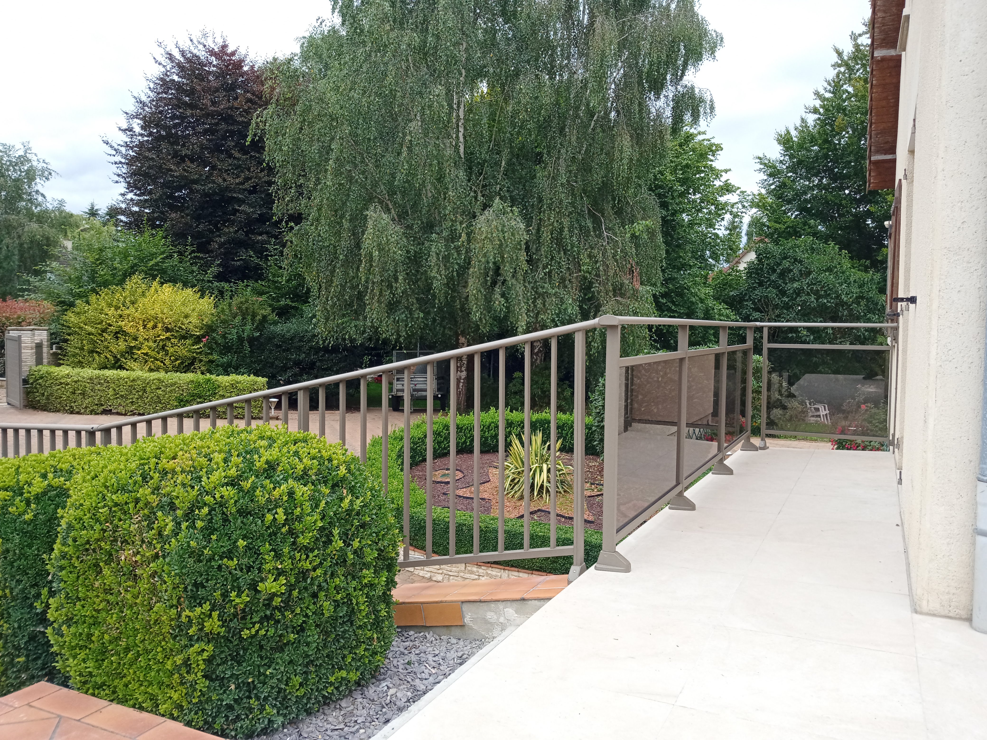 Allée et balustrade donnant sur un jardin verdoyant.