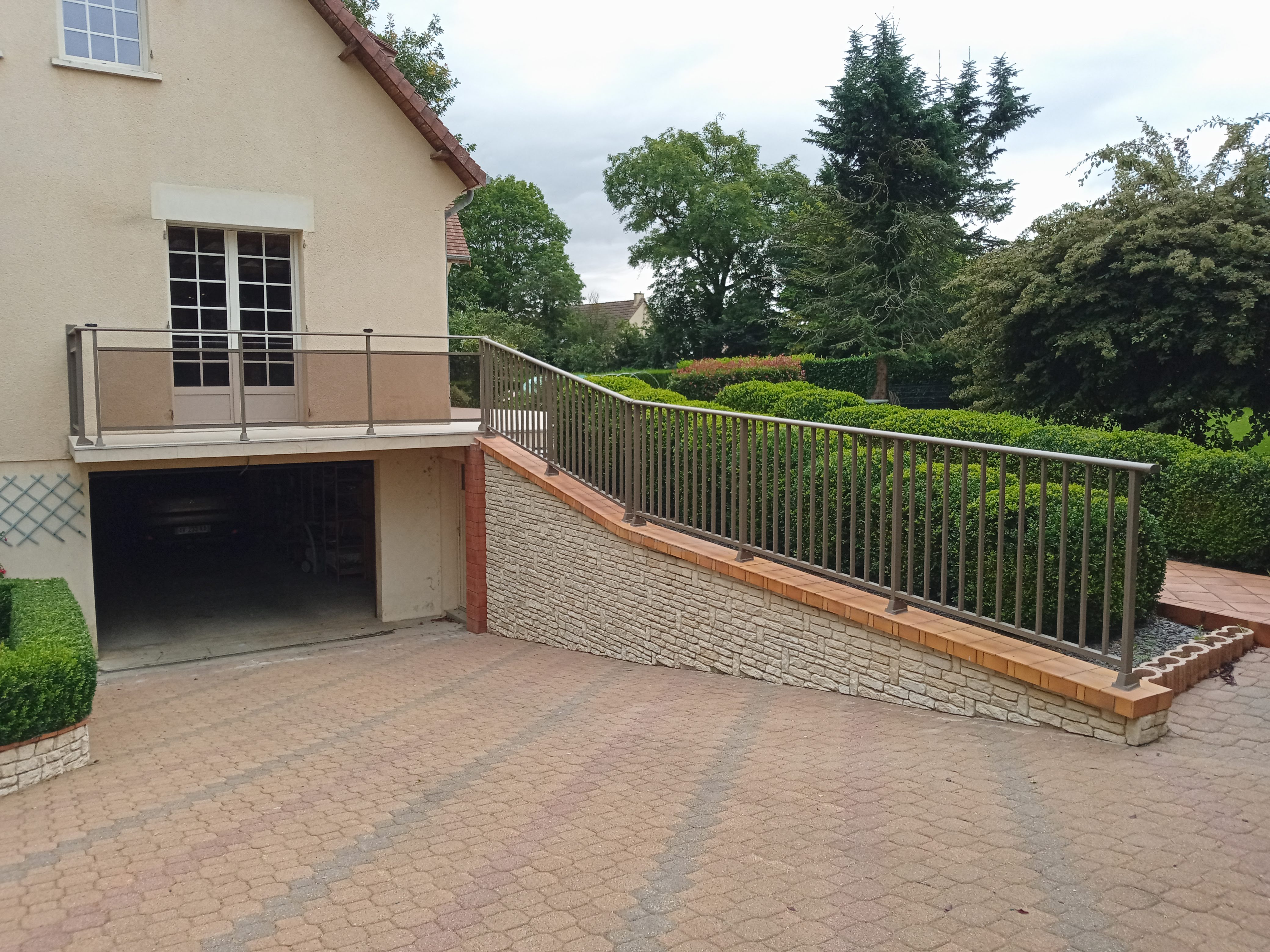 Maison avec rampe d'accès et jardin verdoyant.