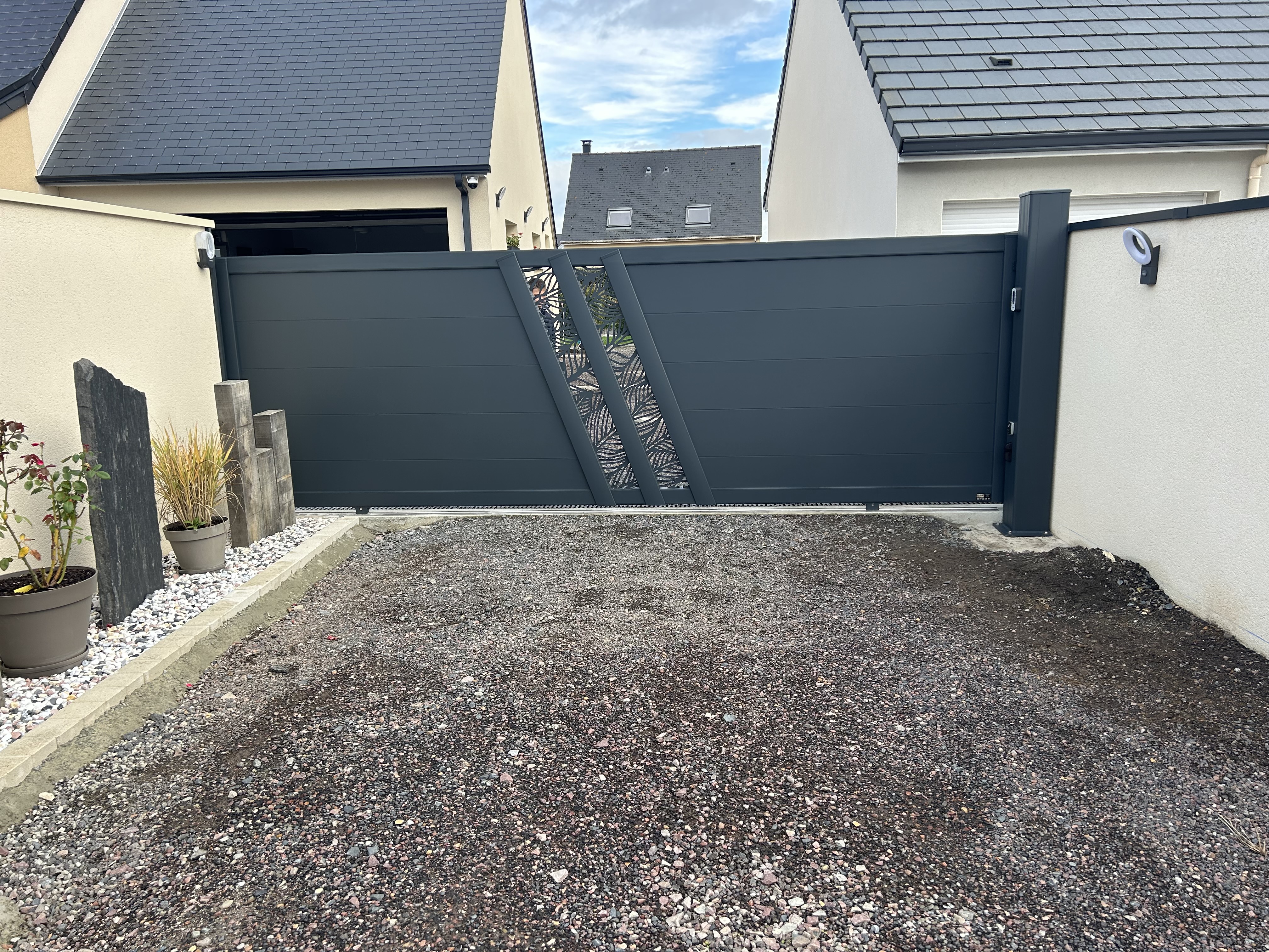 Portail noir moderne devant maison.