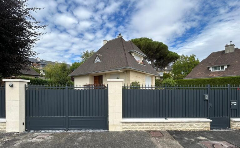 Maison moderne avec jardin, clôture noire.