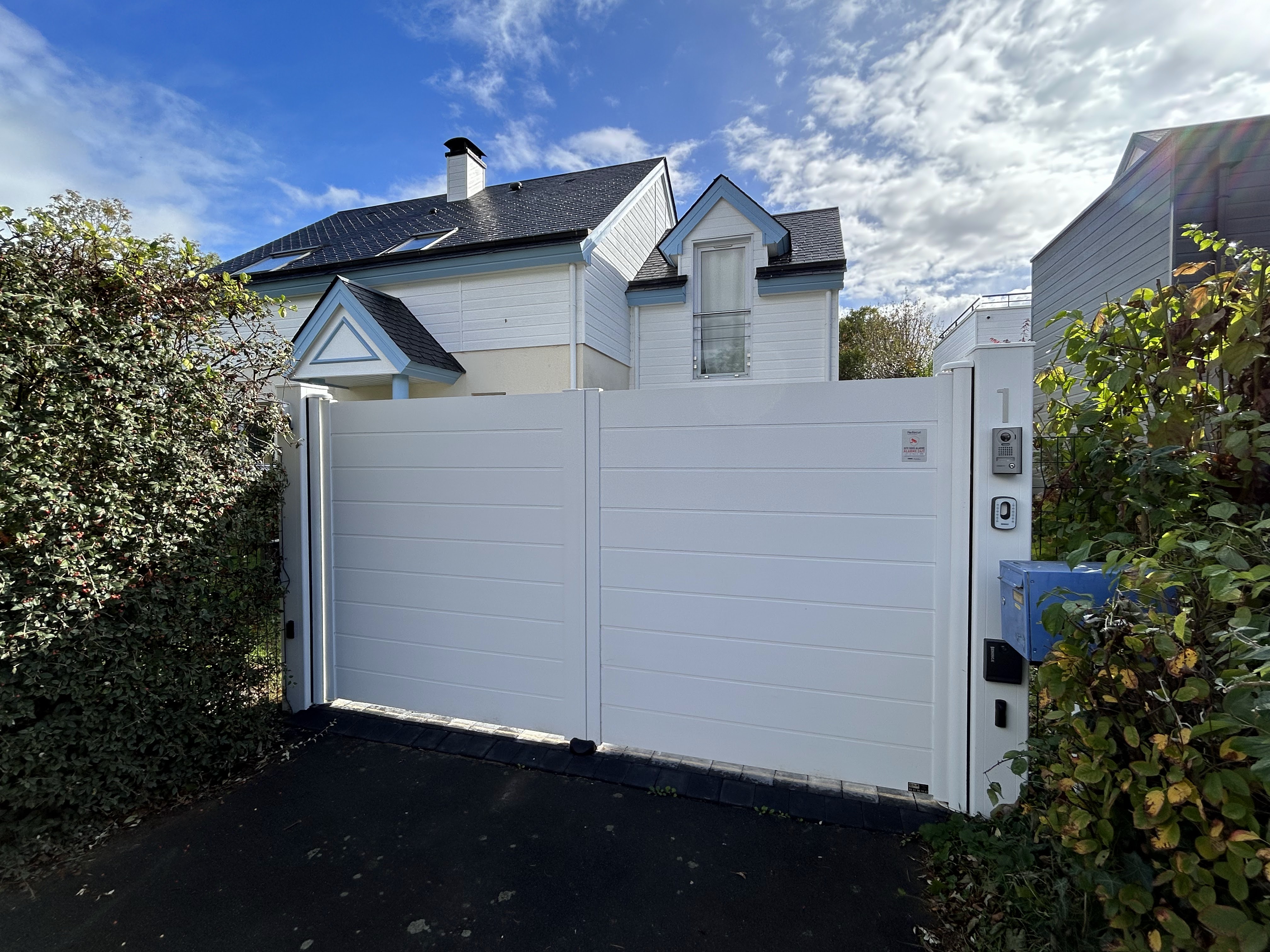 Portail blanc fermé devant maison moderne.