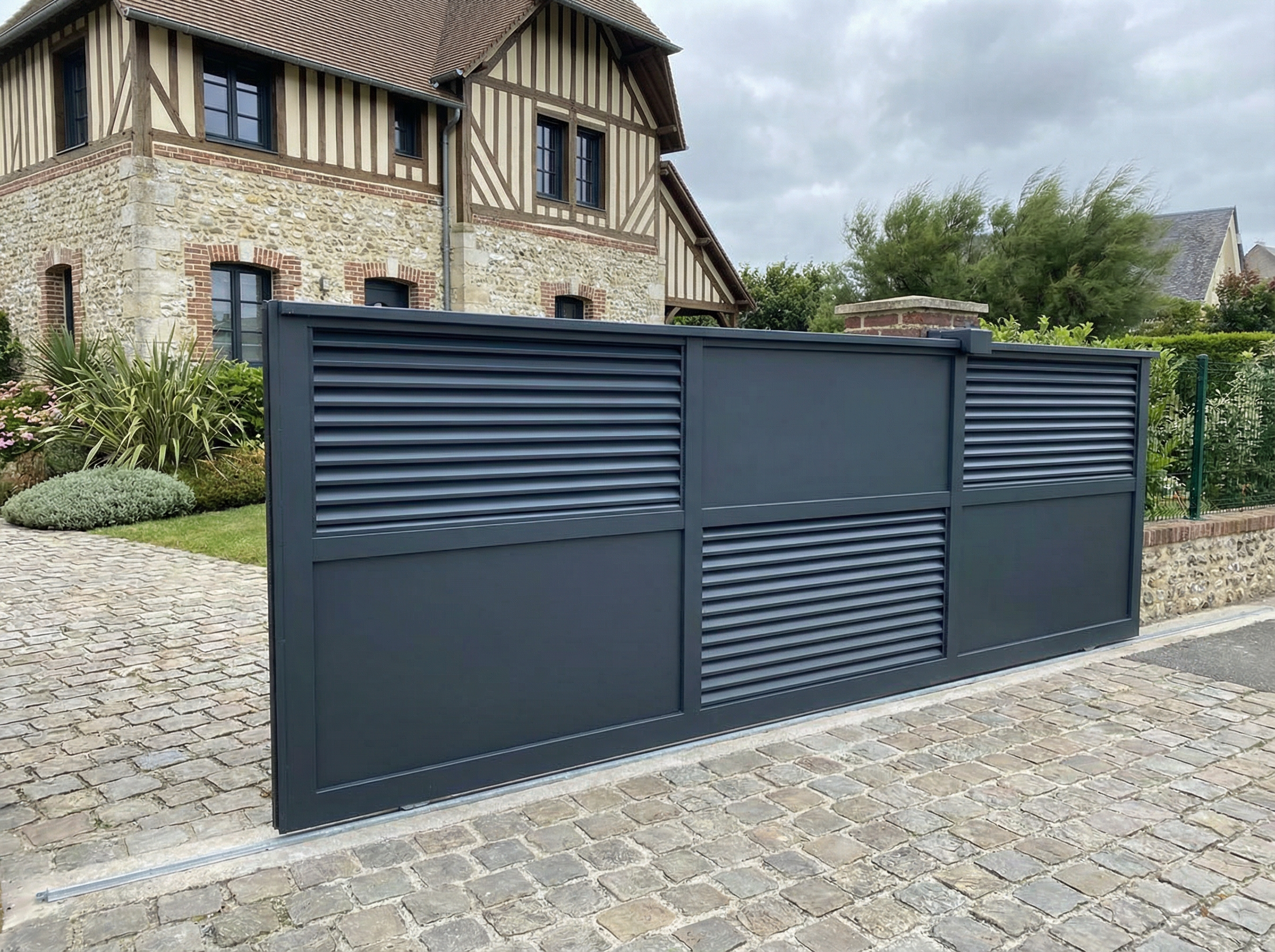 Portail gris moderne devant maison traditionnelle